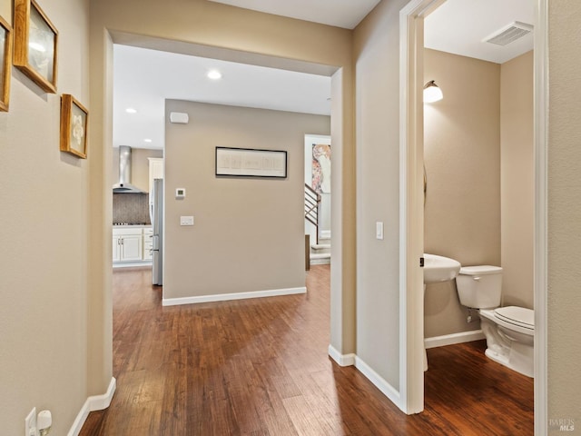 hall with dark wood-style floors, visible vents, and baseboards