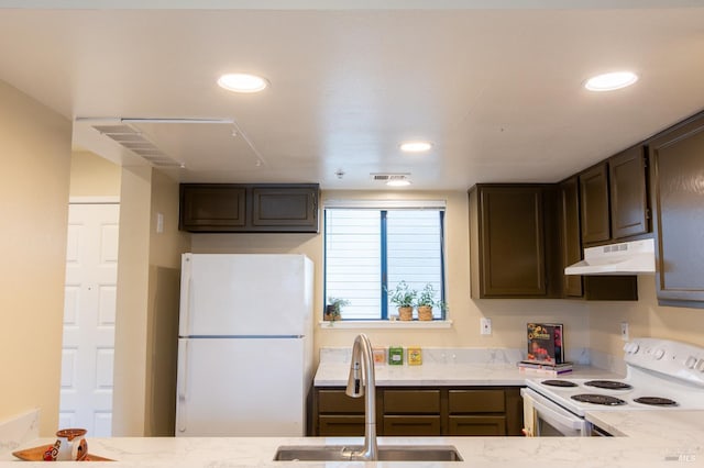 kitchen with dark brown cabinetry, recessed lighting, under cabinet range hood, white appliances, and a sink