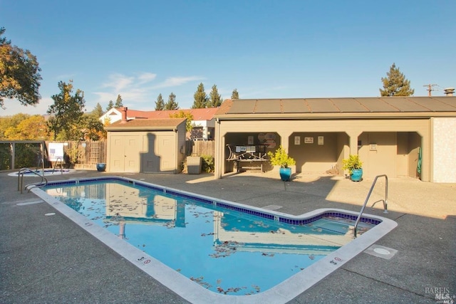 community pool featuring a storage shed, fence, an outdoor structure, and a patio