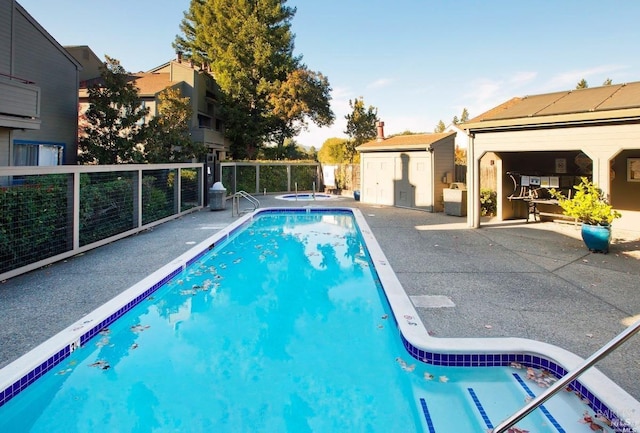 pool featuring fence, a storage unit, an outbuilding, and a patio