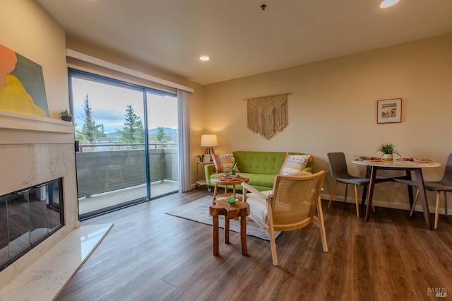 living area featuring a high end fireplace, recessed lighting, baseboards, and wood finished floors