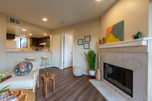 living room with dark wood-style flooring, recessed lighting, visible vents, a high end fireplace, and baseboards