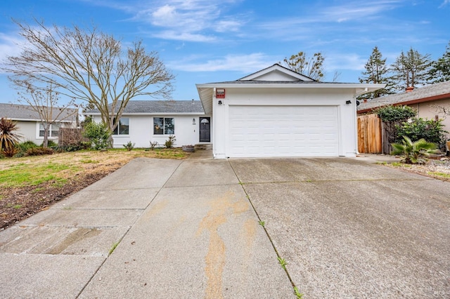 ranch-style house featuring concrete driveway, an attached garage, fence, and stucco siding