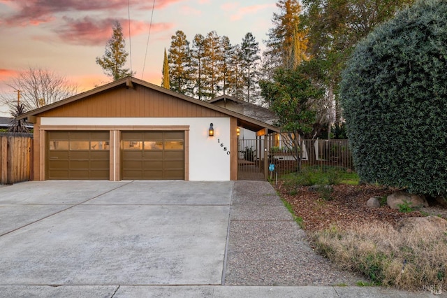 view of front of property featuring a garage, driveway, and fence