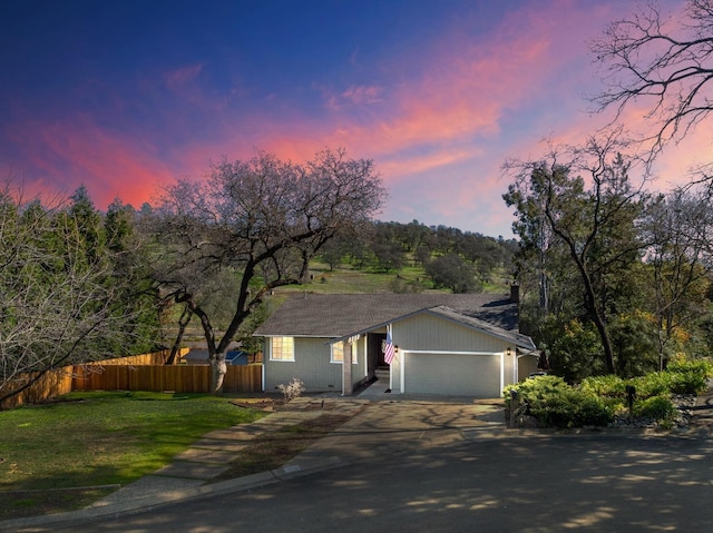 view of front of property with a garage, concrete driveway, a front lawn, and fence