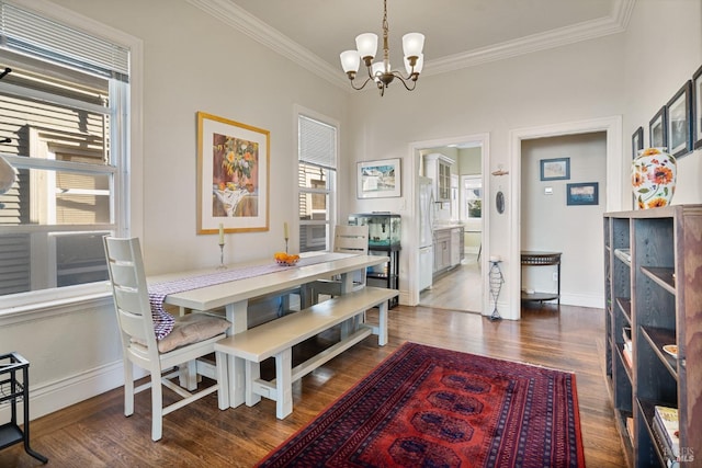 dining area featuring a chandelier, ornamental molding, baseboards, and wood finished floors