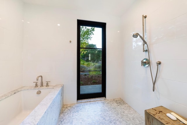 bathroom with a tub to relax in and tile walls