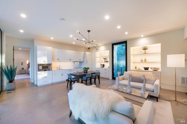living area featuring concrete flooring, visible vents, recessed lighting, a chandelier, and built in shelves
