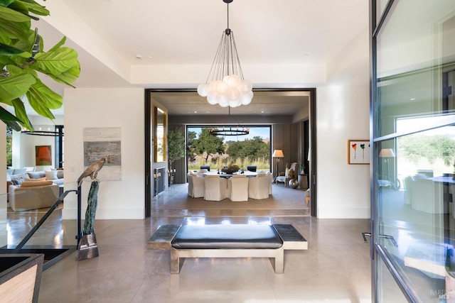 entryway featuring finished concrete flooring, an inviting chandelier, and baseboards
