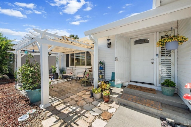 view of exterior entry featuring a patio area and a pergola