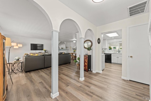 interior space with decorative columns, visible vents, and light wood-style floors