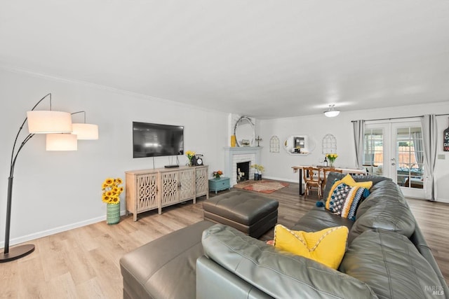 living room featuring a fireplace, baseboards, wood finished floors, and french doors