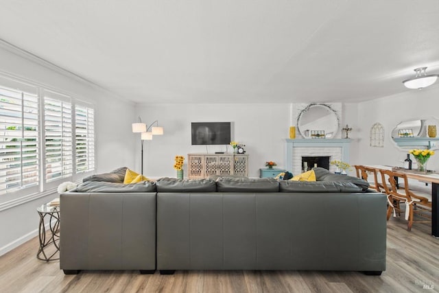 living area featuring a brick fireplace, baseboards, and wood finished floors