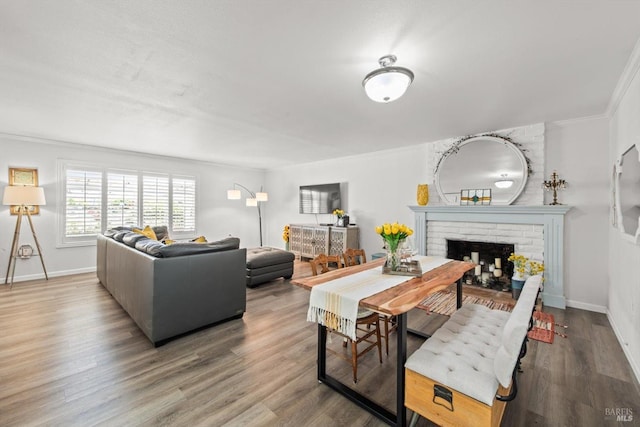 living room featuring crown molding, a fireplace, baseboards, and wood finished floors