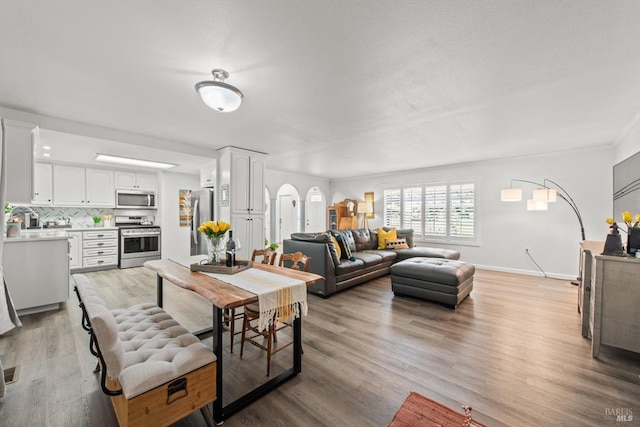 dining room with light wood-type flooring, baseboards, and arched walkways