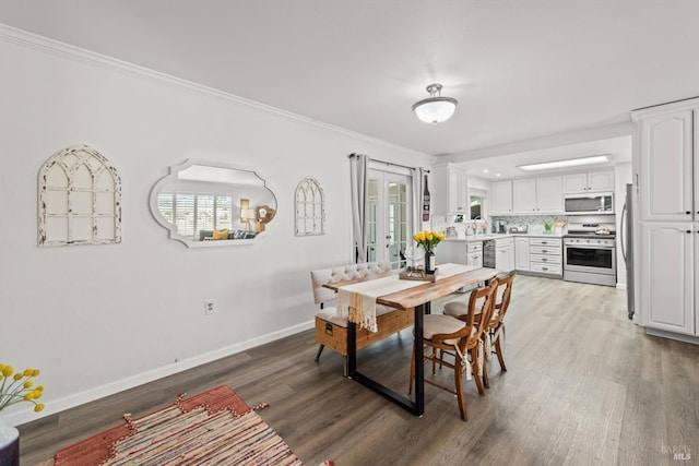 dining space featuring baseboards, french doors, light wood-style floors, and crown molding