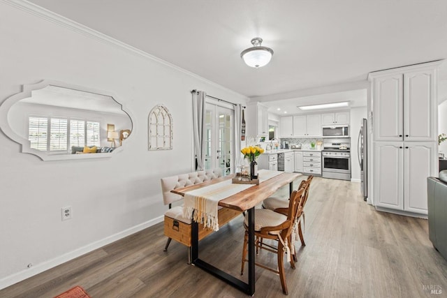 dining area featuring ornamental molding, wood finished floors, and baseboards