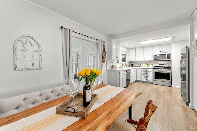 kitchen featuring stainless steel appliances, a sink, white cabinetry, light countertops, and backsplash