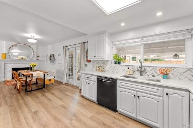 kitchen featuring plenty of natural light, black dishwasher, a sink, and light wood finished floors