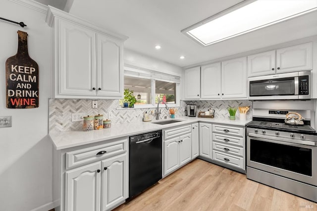 kitchen featuring decorative backsplash, appliances with stainless steel finishes, light wood-type flooring, white cabinetry, and a sink