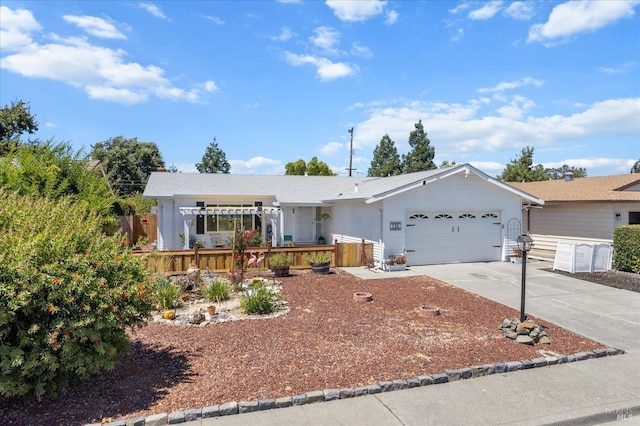 ranch-style house with an attached garage, fence, concrete driveway, a wooden deck, and a pergola