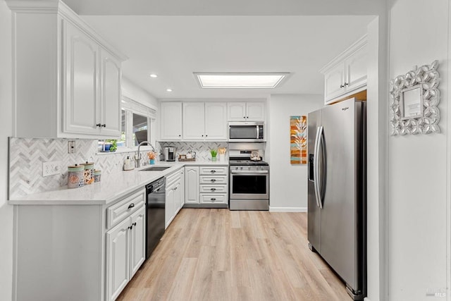 kitchen featuring stainless steel appliances, a sink, white cabinetry, and decorative backsplash