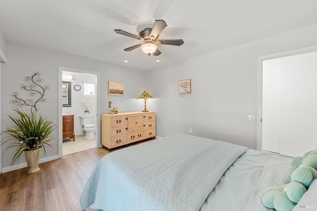 bedroom featuring light wood finished floors, recessed lighting, a ceiling fan, ensuite bath, and baseboards