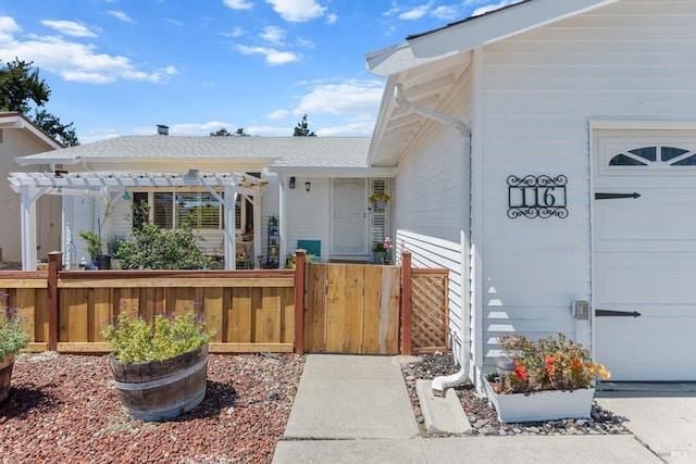 property entrance with a garage, fence, and a pergola