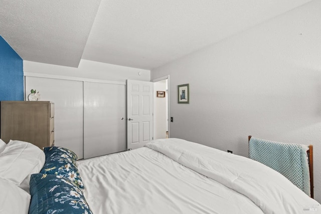 bedroom featuring a closet, a textured wall, and a textured ceiling