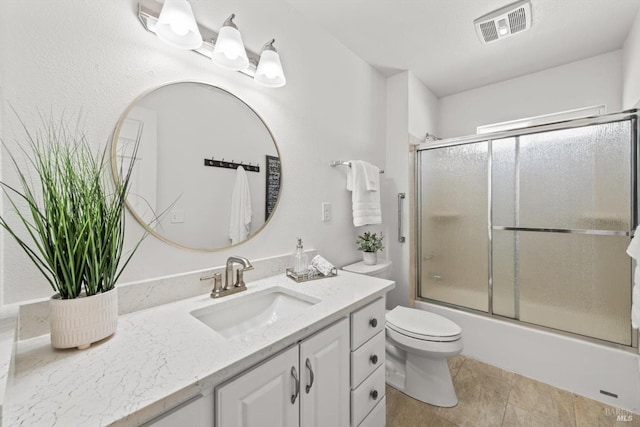 bathroom featuring visible vents, vanity, toilet, and bath / shower combo with glass door