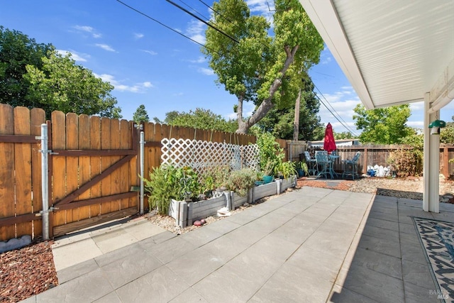 view of patio with a gate, fence, and a vegetable garden