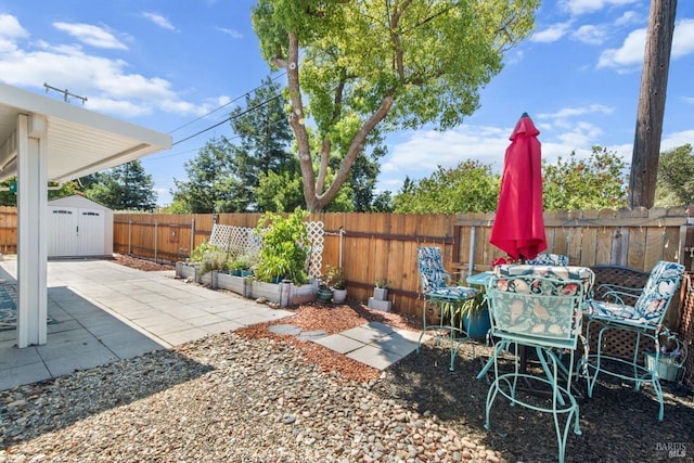 view of yard with an outbuilding, a patio, a fenced backyard, a shed, and outdoor dining space