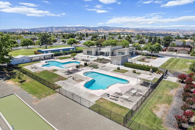 community pool with a patio area, fence, and a mountain view