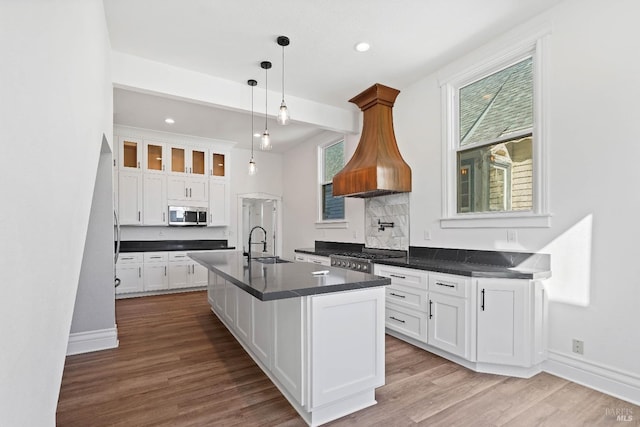 kitchen with stainless steel microwave, dark countertops, a sink, and white cabinets