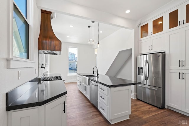 kitchen with appliances with stainless steel finishes, dark countertops, dark wood finished floors, and a sink