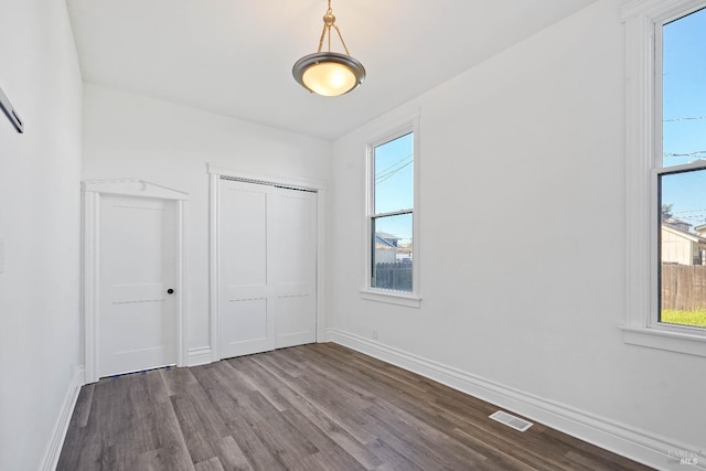 unfurnished bedroom with visible vents, dark wood finished floors, baseboards, and multiple windows