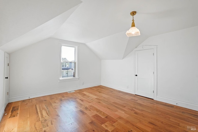 additional living space featuring visible vents, lofted ceiling, light wood-style flooring, and baseboards