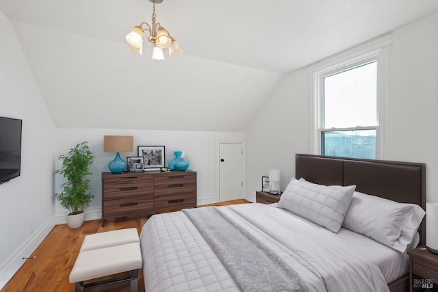 bedroom with lofted ceiling, an inviting chandelier, wood finished floors, and baseboards