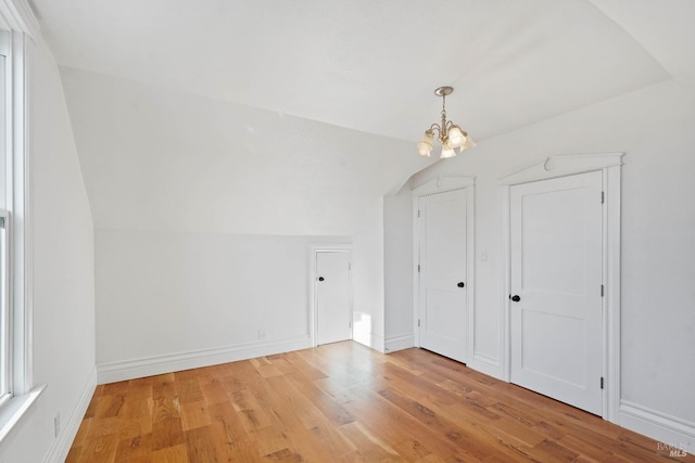 additional living space featuring lofted ceiling, an inviting chandelier, light wood-style flooring, and baseboards