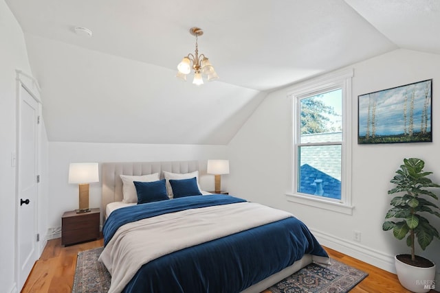 bedroom featuring lofted ceiling, a notable chandelier, baseboards, and wood finished floors