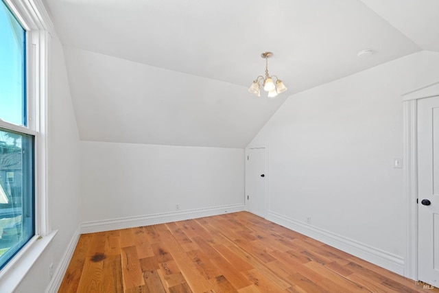 additional living space featuring lofted ceiling, light wood-type flooring, a chandelier, and baseboards