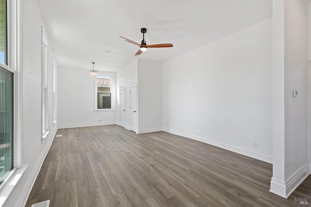 unfurnished living room featuring dark wood-type flooring, ceiling fan, and baseboards