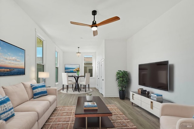 living area with baseboards, a ceiling fan, and wood finished floors