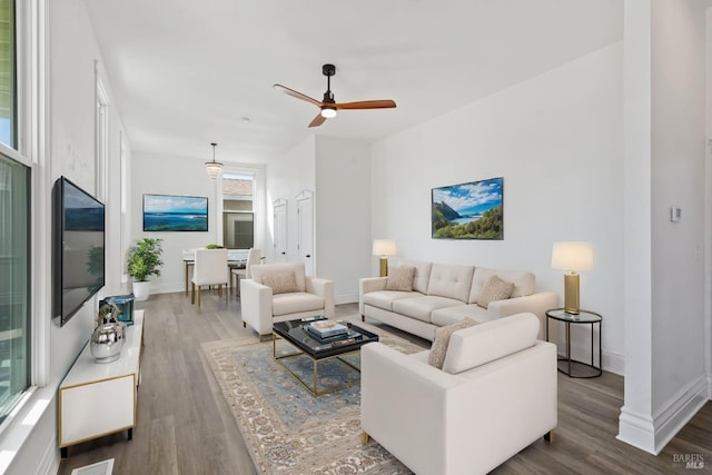 living room featuring ceiling fan, baseboards, and wood finished floors