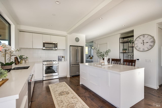 kitchen featuring dark wood finished floors, a center island, stainless steel appliances, white cabinetry, and backsplash