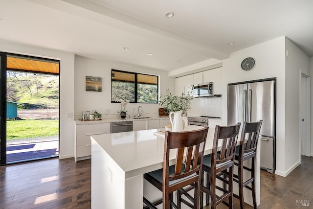 kitchen with dark wood finished floors, appliances with stainless steel finishes, light countertops, white cabinetry, and a sink