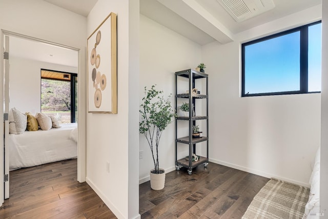 hall featuring dark wood-type flooring, visible vents, and baseboards