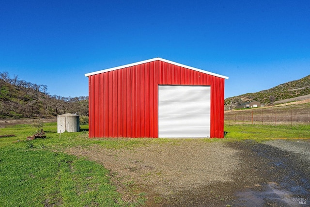 view of outdoor structure featuring an outbuilding, fence, and a mountain view