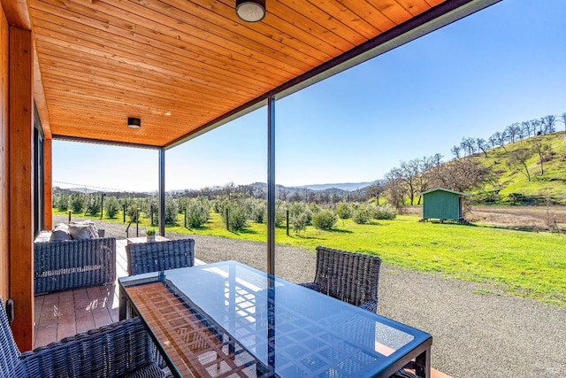 view of patio / terrace featuring a mountain view, a storage unit, an outdoor structure, and outdoor dining space