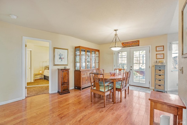 dining area with light wood-style floors, baseboards, and french doors